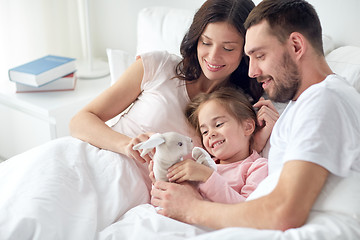 Image showing happy child with toy and parents in bed at home