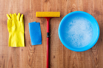 Image showing basin with cleaning stuff on wooden background