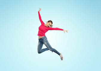 Image showing happy young woman jumping in air or dancing