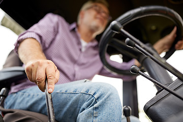 Image showing senior man driving tractor at farm