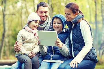 Image showing family sitting on bench with tablet pc at camp