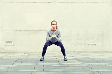 Image showing woman doing squats and exercising outdoors