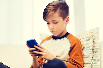 Image showing boy with smartphone texting or playing at home