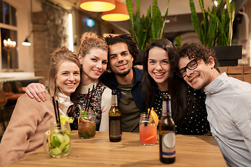 Image showing happy friends with drinks at bar or cafe