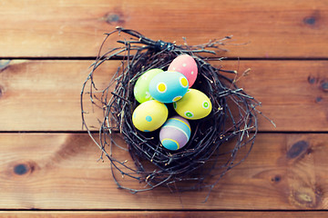 Image showing close up of colored easter eggs in nest on wood