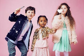 Image showing lifestyle people concept: diverse nation children playing together, caucasian boy with african little girl holding candy happy smiling 