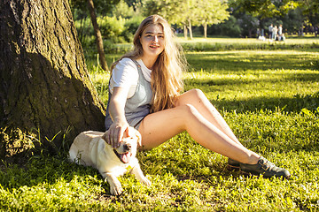 Image showing young attractive blond woman playing with her dog in green park at summer, lifestyle people concept