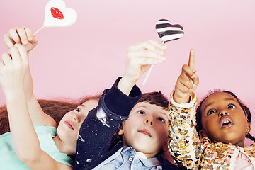 Image showing lifestyle people concept: diverse nation children playing together, caucasian boy with african little girl holding candy happy smiling 