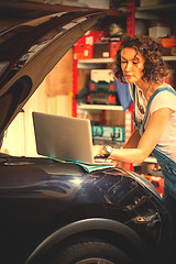 Image showing Beautiful woman mechanic near a car