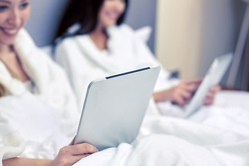 Image showing happy women in bathrobes with tablet pc at hotel