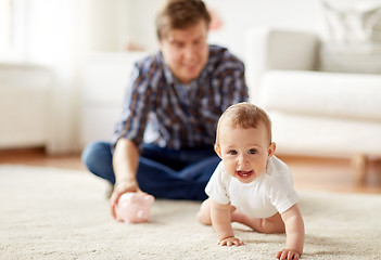 Image showing happy father with baby and piggy bank at home