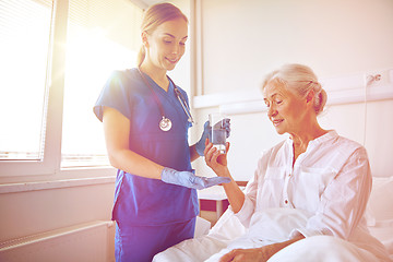 Image showing nurse giving medicine to senior woman at hospital