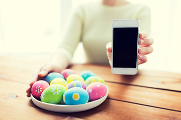 Image showing close up of hands with easter eggs and smartphone