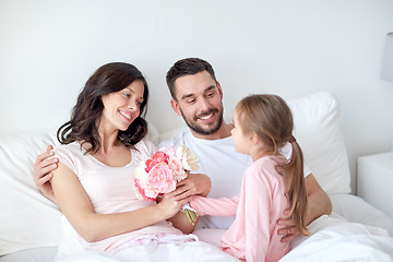 Image showing happy girl giving flowers to mother in bed at home