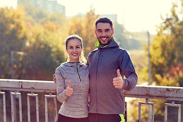 Image showing smiling couple showing thumbs up outdoors