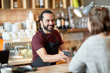 Image showing man or waiter with card reader and customer at bar