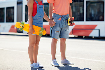 Image showing close up of young couple with skateboards in city