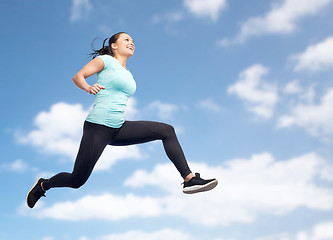 Image showing happy smiling sporty young woman jumping in air