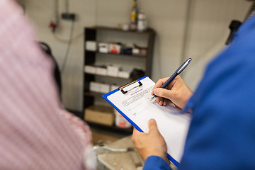 Image showing auto mechanic with clipboard and man at car shop