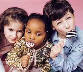 Image showing lifestyle people concept: diverse nation children playing together, caucasian boy with african little girl holding candy happy smiling 