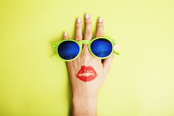 Image showing woman hand holding sunglasses on bright background, cosmetic summer vacation concept