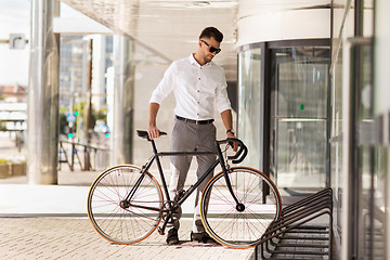 Image showing young man parking his bicycle on city street