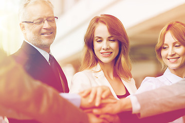 Image showing business people putting hands on top in office