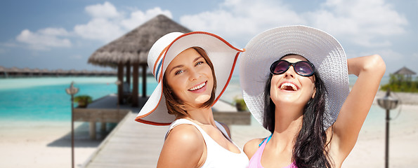 Image showing smiling young women in hats on beach