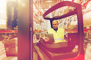 Image showing man with tablet pc operating forklift at warehouse