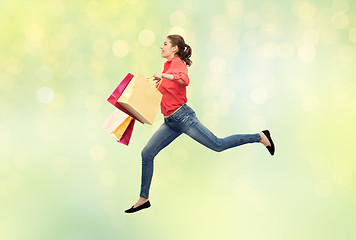 Image showing smiling young woman with shopping bags jumping