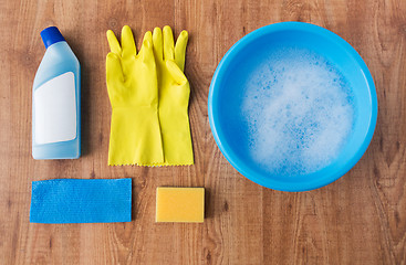 Image showing basin with cleaning stuff on wooden background