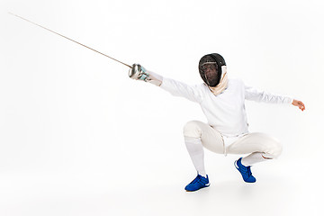 Image showing Man wearing fencing suit practicing with sword against gray