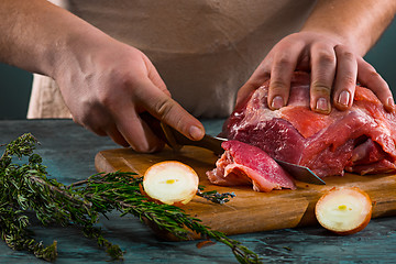 Image showing Butcher cutting pork meat on kitchen