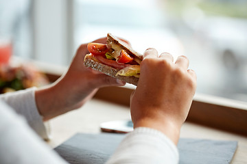 Image showing woman eating salmon panini sandwich at restaurant