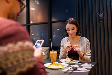 Image showing happy couple with smartphones at vegan restaurant
