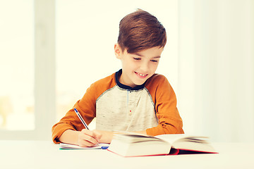 Image showing smiling student boy writing to notebook at home