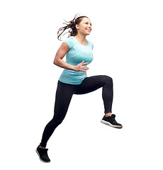 Image showing happy smiling sporty young woman jumping in air