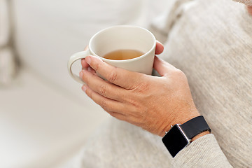 Image showing close up of senior man with tea and wristwatch