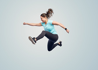 Image showing happy smiling sporty young woman jumping in air
