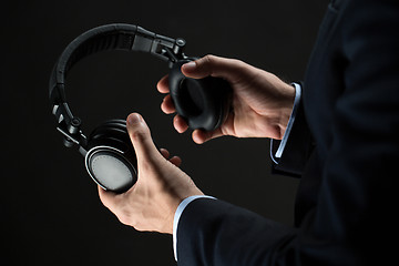 Image showing close up of businessman hands holding headphones