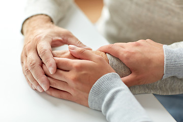 Image showing close up of old man and young woman holding hands