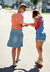 Image showing teenage couple riding skateboard on city street