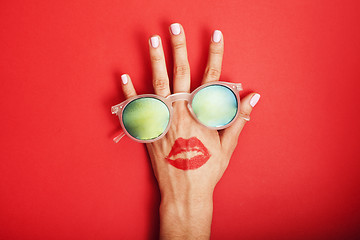 Image showing woman hand holding sunglasses on bright background, cosmetic summer vacation concept