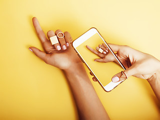 Image showing womans hand taking picture of her new manicure with fashion jewellery on her phone, girls stuff concept