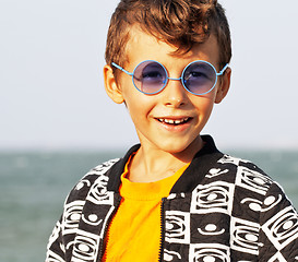 Image showing cute little boy at seacoast in fashion clothers and blue glasses