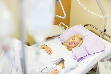 Image showing Bedridden female patient recovering after surgery in hospital care.