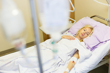 Image showing Bedridden female patient recovering after surgery in hospital care.