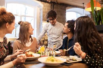 Image showing happy friends eating and drinking at restaurant