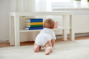 Image showing little baby in diaper crawling on floor at home