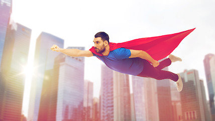 Image showing man in red superhero cape flying over city